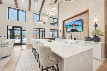 A modern kitchen with a large island and a painting of a beach scene on the wall.